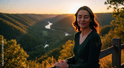 Uma mulher no topo da montanha respirando fundo e sorrindo.