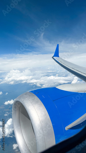 Aerial view of aircraft wing and jet engine with blue sky and clouds for aviation and travel concept of airline, travel agency, aviation magazine