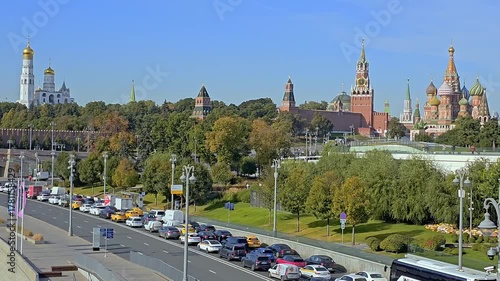 Russia, Moscow - October 01, 2025: Scenic view of the Moscow Kremlin, Cathedral of the Annunciation, and Saint Basil Cathedral along the Moskva River with cars driving on the embankment under clear bl