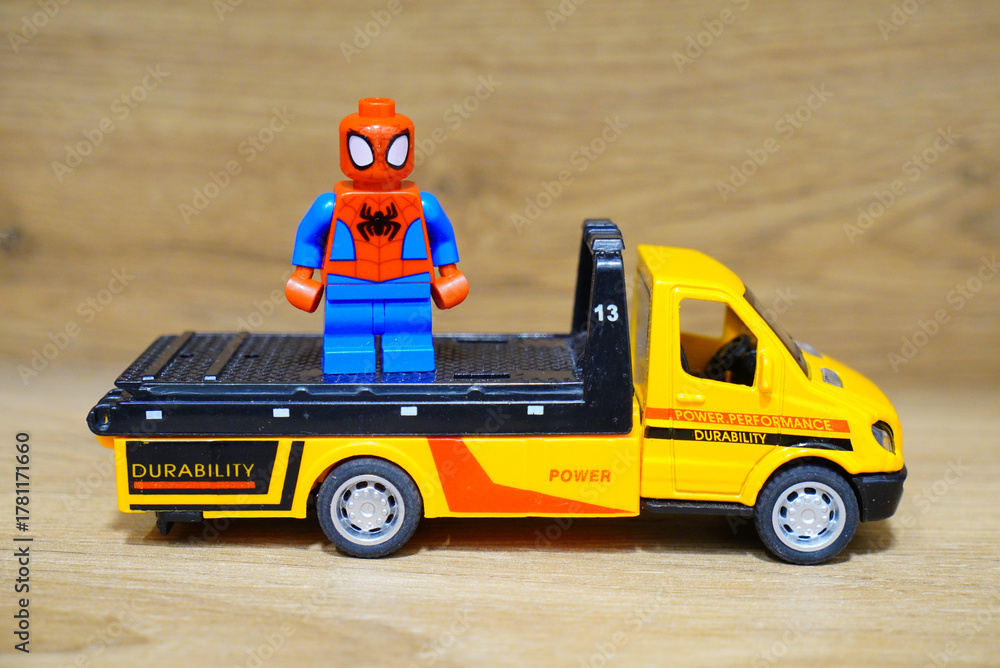 Obraz premium Spider-Man toy figure stands on a yellow toy truck on a wooden surface