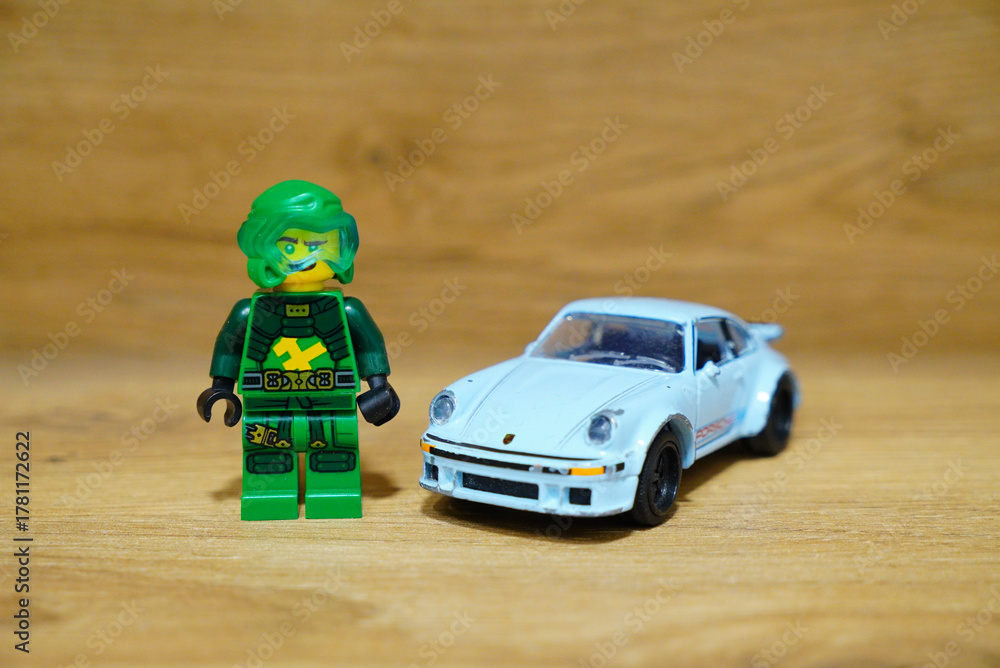 Fototapeta premium Lego minifigure and a classic Porsche sports car on a wooden surface