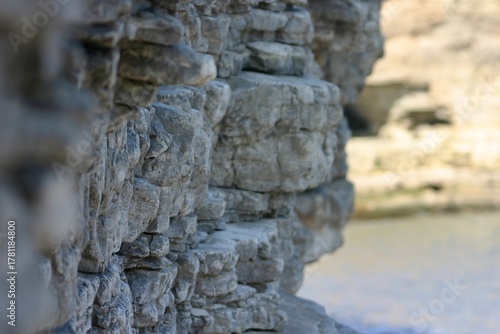 Tableau sur toile Layered coastal rock formation captured in soft daylight, showing natural erosion, texture, and geological detail near the sea