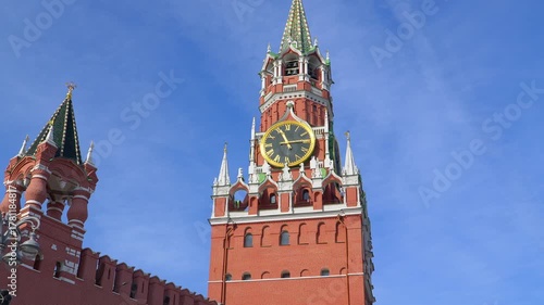 Spasskaya Tower clock on Moscow Kremlin with golden face and Roman numerals against red brick architecture. Famous Russian landmark timepiece showing historic ornate design under clear blue sky.