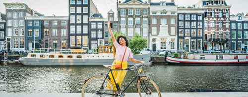 Canvas Print Happy female tourist visiting Amsterdam city, Netherlands - Delightful woman rid