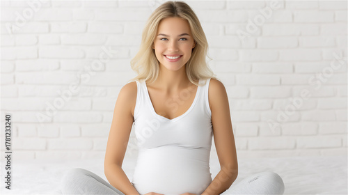 Smiling woman sitting cross-legged in white top, natural light and minimal home interior, concept of wellbeing and relaxation.