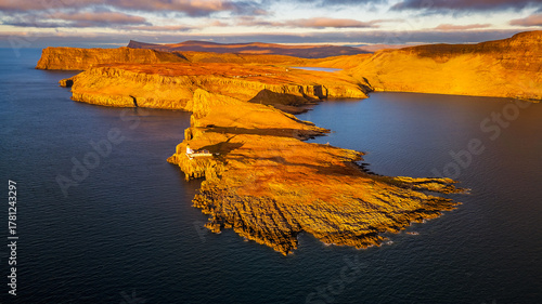 Wallpaper Mural Aerial view of Neist Point Lighthouse at sunset, Isle of Skye, Scotland, with golden cliffs glowing in warm evening light above the blue Atlantic Ocean. Torontodigital.ca