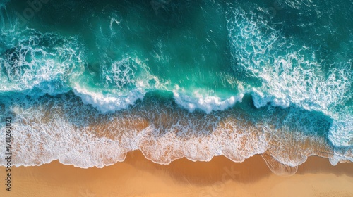 Fototapeta Naklejka Na Ścianę i Meble -  Aerial view of ocean wave crashing on sandy beach with white foam