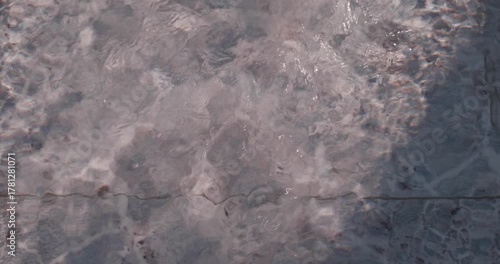 Close-up of water flowing into a shallow pool creating ripples and reflections