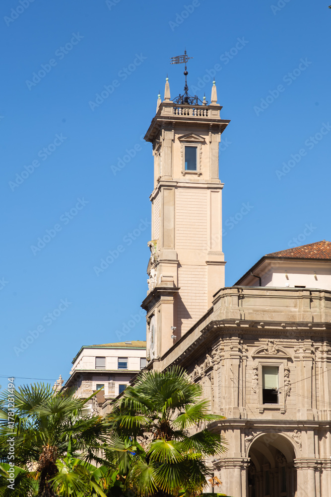Fototapeta premium Historical Tower under the Sky: The photo showcases a tall, historic tower with intricate architectural details against a clear, sunny sky, creating a picturesque scene.