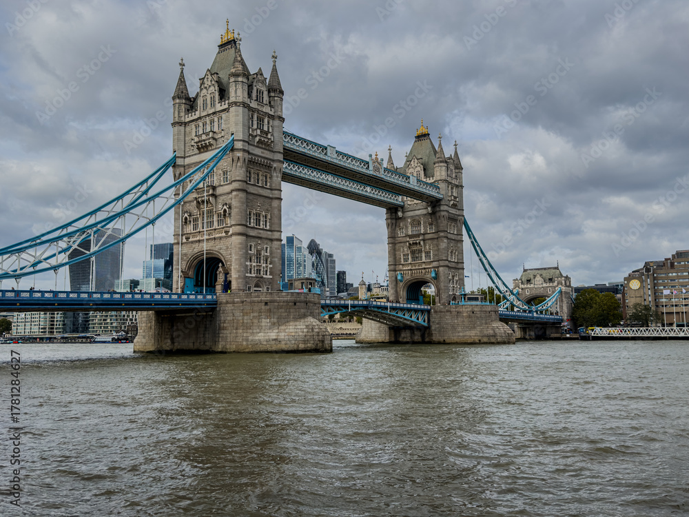Fototapeta premium Stunning aerial view of Tower Bridge in London, spanning the River Thames with the city skyline in the background — blending historic architecture and modern urban beauty. London Bridge