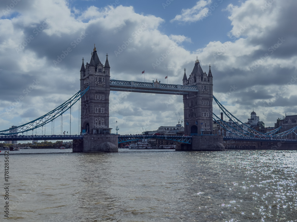 Fototapeta premium Stunning aerial view of Tower Bridge in London, spanning the River Thames with the city skyline in the background — blending historic architecture and modern urban beauty. London Bridge