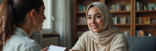 Muslim woman in hijab during consultation with professional advisor. Muslim woman smiling listens attentively during meeting, taking notes for future reference, perhaps financial or career advice.