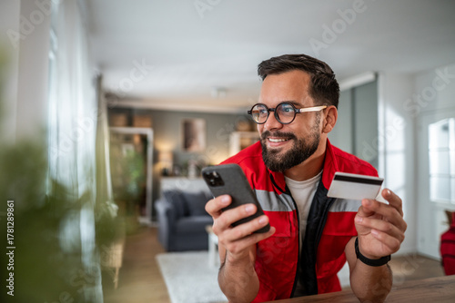 Man shopping online using smartphone and credit card at home