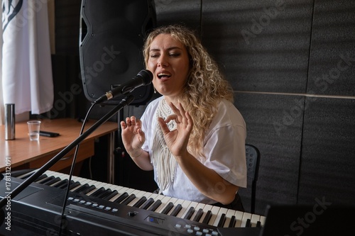 Obraz na płótnie Caucasian woman singing into microphone and playing synthesizer and recording herself on laptop