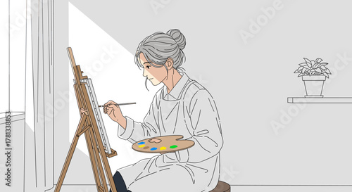 Elderly asian female artist focused on painting while seated at an easel in a brightly lit room.