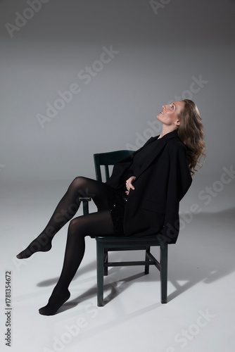 Full length image of elegant, sensual young woman wearing in black clothes, looking at the side, posing in studio, isolated grey background. 