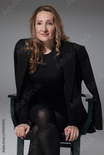 Front image of elegant, sensual young woman wearing in black clothes, posing in studio, isolated grey background. 