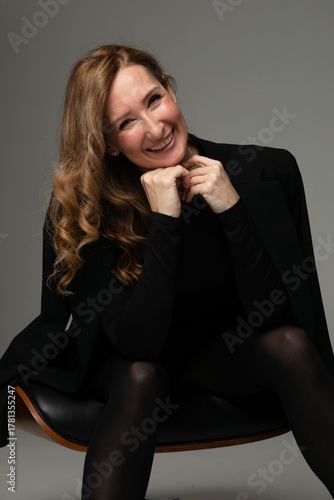 Happy young woman with makeup and curly hair, posing in studio, looking at camera.