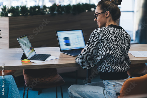 Modern businesswoman working with multiple digital devices, turning away from screen while multitasking, illustrating confidence, control and data-driven decision-making on the go.