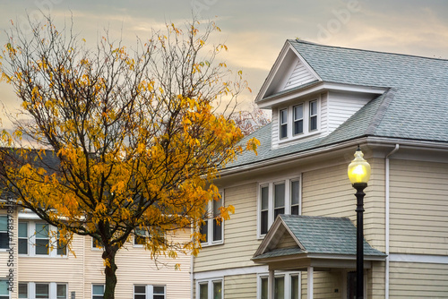 Photos Beige gabled home with autumn tree and glowing streetlamp on a late afternoon in