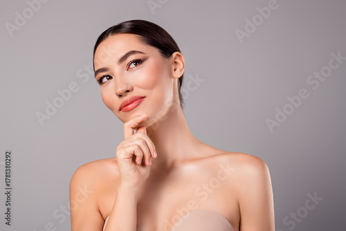 Portrait of a stylish young woman expressing confidence and charm on a neutral gray background
