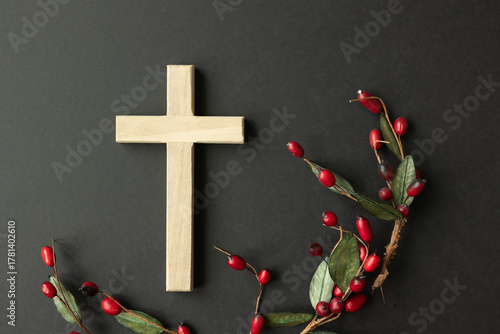 Wood cross with red holly berry border on a black background
