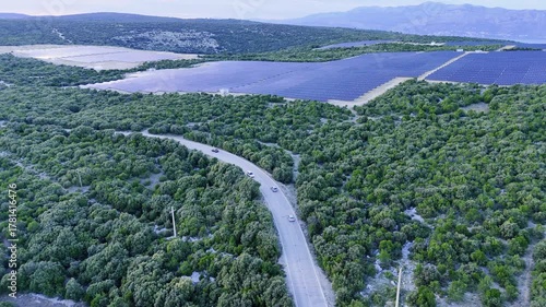 Aerial of electric cars driving near big solar panel photovoltaic energy plant