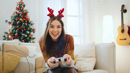 Happy woman enjoys a festive atmosphere playing video games together while surrounded by Christmas decorations and a tree.