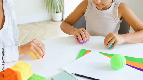 Children's therapy session focusing on speech improvement using hands-on activities and sensory toys in a bright, modern setting