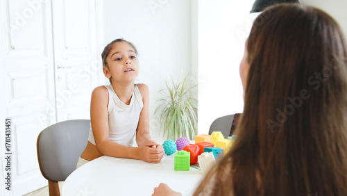 Session between speech therapist and child focused on letter recognition with alphabet and communication skills in a bright, modern therapy room with educational toys