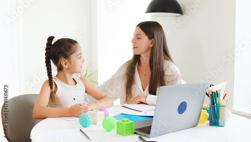 Engaging speech therapy session between a speech therapist and child in a bright, modern workspace with educational tools and laptop