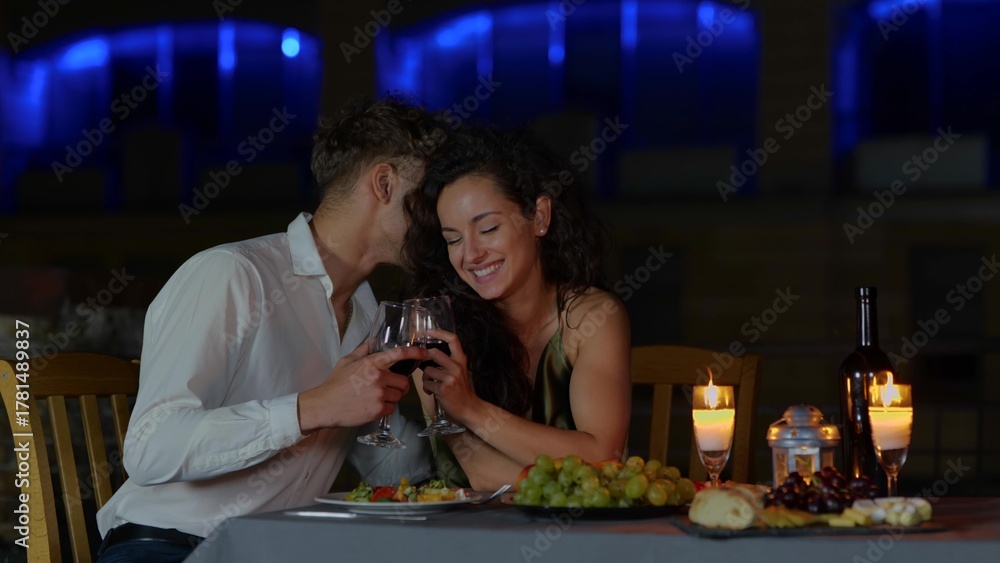 © Vlad - Close up of happy passionate couple in love drinking wine at romantic date and flirting. Handsome loving husband whispering on ear beautiful young wife. Dating concept