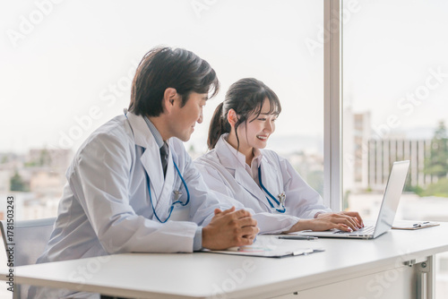 A male supervising doctor and a female trainee doctor are receiving training while looking at electronic medical records on a computer
