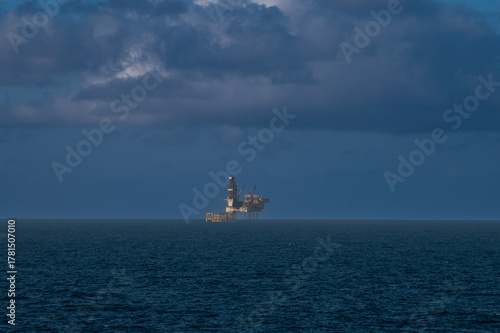 Offshore oil platform, drilling rig, and supply boat at twilight