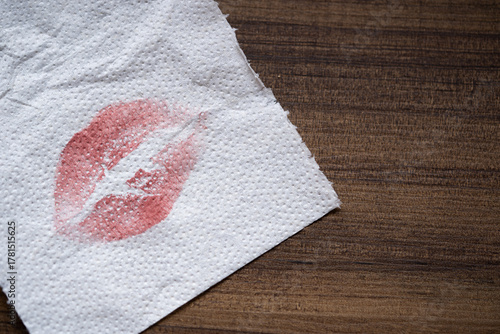 servilleta de papel blanca con mancha de lápiz labial rojo sobre mesa de madera