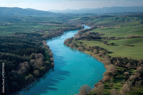 Serene aerial view reveals a winding turquoise river through rolling green hills and valleys on a
