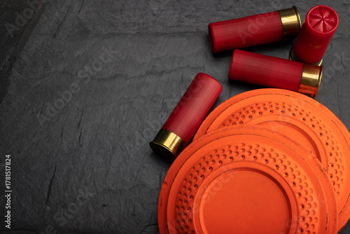 Clay shooting target with shotgun shell on black slate background , Shotgun game
