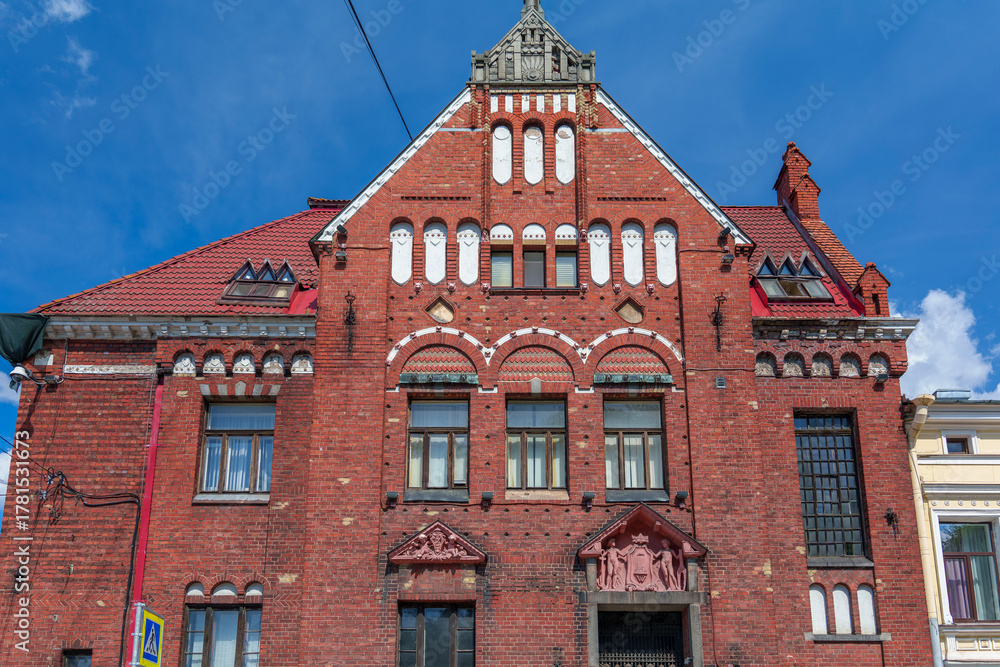Fototapeta premium Historic red brick building with ornate facade under blue sky