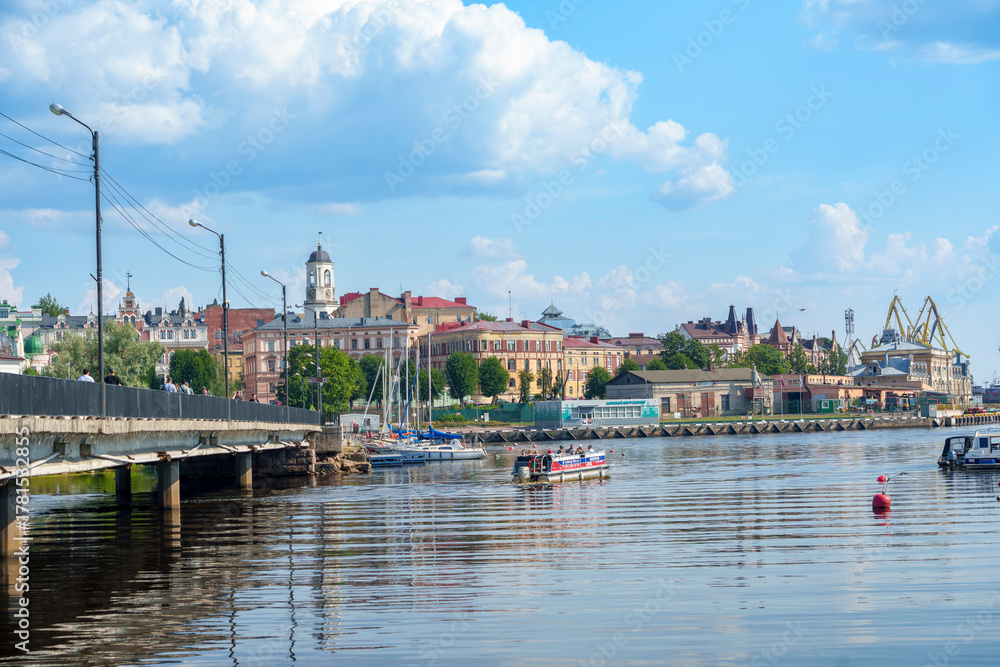 Obraz premium Historic waterfront cityscape with bridge and boats on a calm summer day