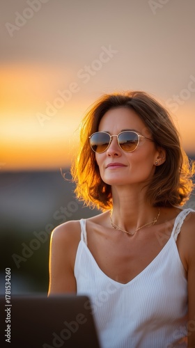 Woman Embracing Sunset Laptop stylish woman enjoys tranquil moment watching vibrant sunset while working her laptop,
