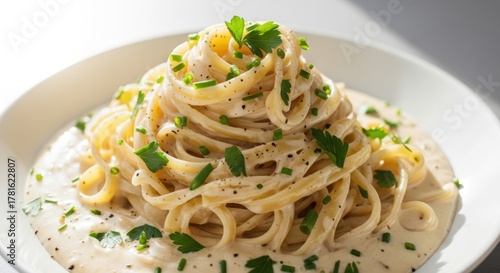 Delicious creamy pasta dish with fresh herbs and black pepper on a white plate