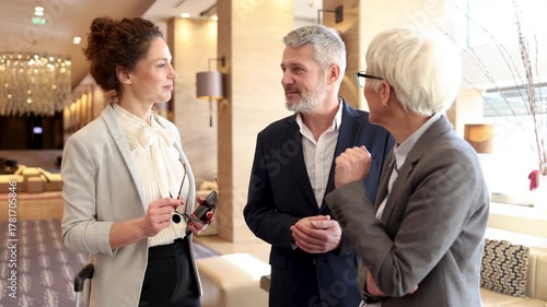 Three experienced professionals chatting casually in a stylish hotel lobby during a corporate excursion
