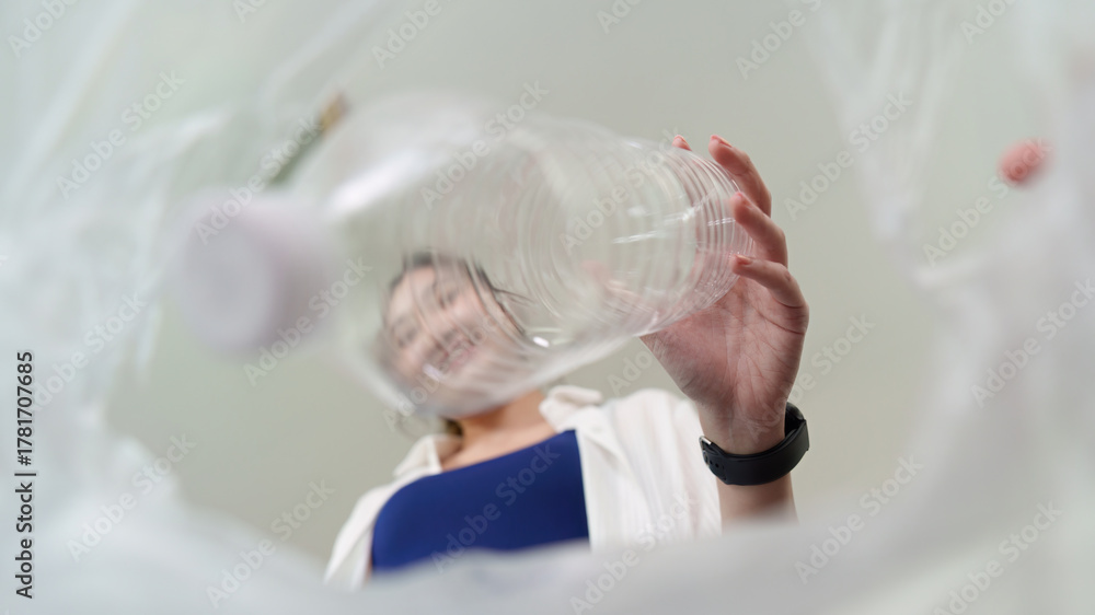 Fototapeta premium Sustainability. Woman recycling plastic bottle, promoting eco-friendly habits.
