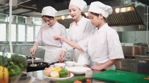 Teenage trainee girls in white aprons practice cooking with master chef in gourmet class school, frying rice in restaurant kitchen, preparing delicious cuisine with ingredients, and culinary meals.
