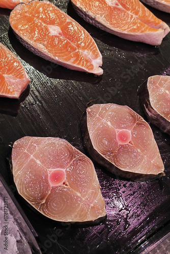 Fresh, prepared king mackerel steak displayed on a vendor's tray at a fish market. For themes usage of healthy food, seafood, gourmet cooking, ketogenic diet and restaurant menus. Real fish meat