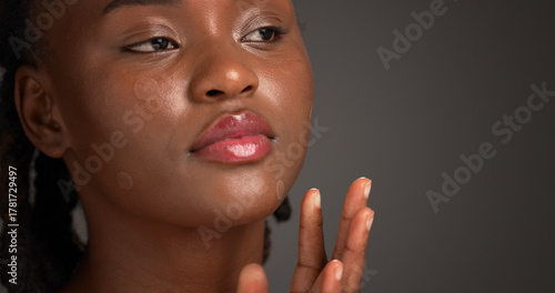 Acne patch, beauty and lip gloss with black woman on studio space for cosmetics or dermatology. Inspection, skincare and treatment with African model isolated on gray background to remove pimple