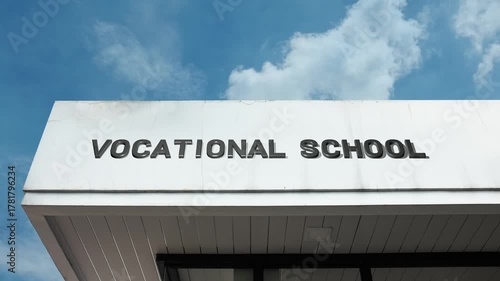 Vocational School word sign displayed on an educational building under a clear blue sky, symbolizing technical training, career education, skill development, practical learning, trade skills