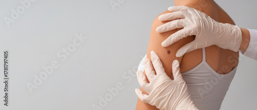 Tableau sur toile Dermatologist examining young woman's mole on light background, closeup