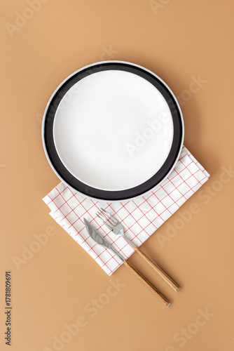 Wallpaper Mural Top view of minimalistic table setting with empty plate, cutlery and napkin on brown background, flat lay Torontodigital.ca