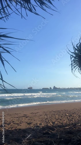The sea in Jember, East Java. Indonesia. Watu Ulo beach with dark sand, mountains and coral rocks towering above the beach. The raging blue Indian ocean on a sunny day. 4К